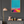 Framed abstract artwork on a dark gray wall with a lamp and small decorative items on a dresser.
