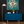 Modern interior with a blue cabinet, gold floor lamp, and abstract eye artwork on a black wall.