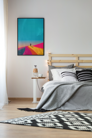 Bedroom with a colorful abstract painting on the wall above a bed.