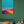 Colorful abstract painting on a green wall above a sofa with cushions and a small table.